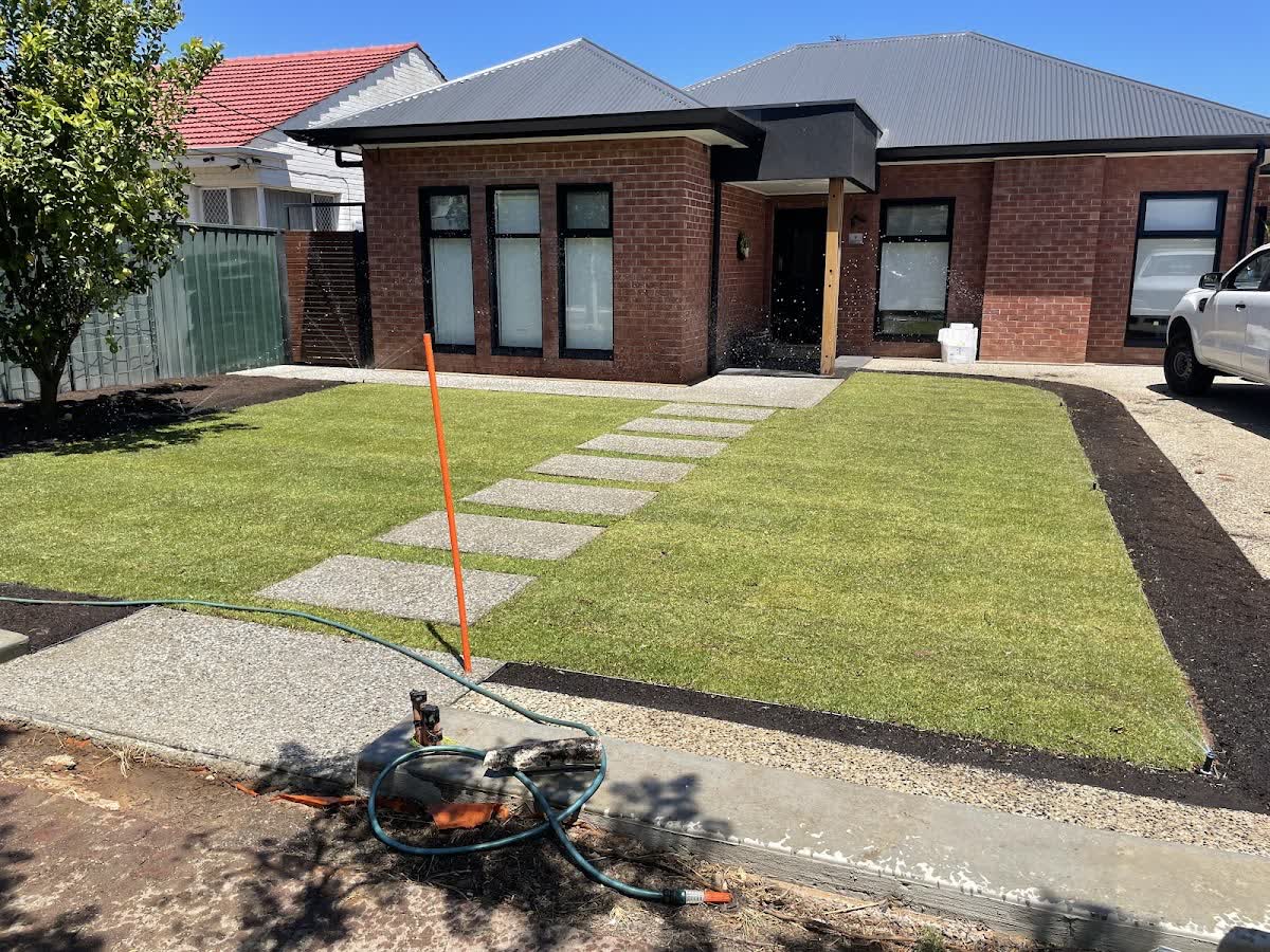 New lawn and paver stepping-stones leading to a brick home's entry